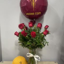 Red roses in a glass vase with an Arizona State balloon and cap