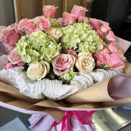 Bouquet of pink and cream roses with green hydrangeas wrapped in paper