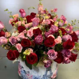 Bouquet of red, pink, and lavender roses in a decorative round box