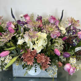 Mixed bouquet of pink and purple flowers in a wooden box