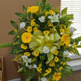 Large yellow and white floral standing spray with a ribbon bow