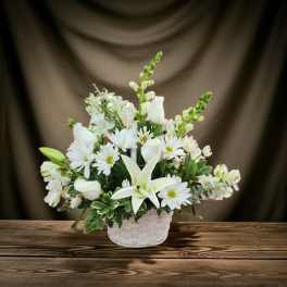 White flowers arranged in a white basket on a wooden table