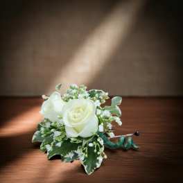 White rose boutonniere with small white filler flowers and variegated leaves