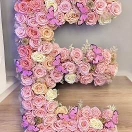 Large floral letter covered in pink and cream roses with butterfly accents