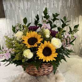 Basket arrangement with sunflowers, white roses, and purple blooms