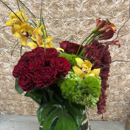 Bouquet of burgundy roses and yellow orchids in a mirrored vase