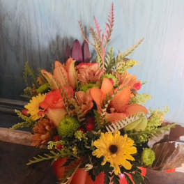 Autumn bouquet in an orange pumpkin container with yellow daisies and orange blooms