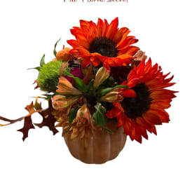 Orange sunflower arrangement in a pumpkin-shaped vase