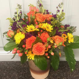 Orange roses and yellow daisies in a ceramic vase