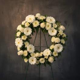 White floral wreath on a stand with daisies and roses
