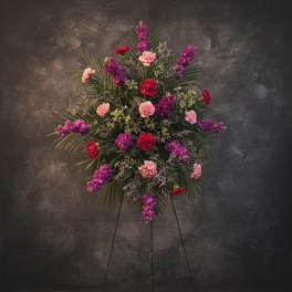 Standing floral spray with pink, purple, and red carnations on an easel