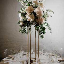 Tall floral centerpiece with blush and white blooms on a gold stand
