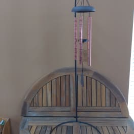 Blue metal wind chime hanging above a wooden bench