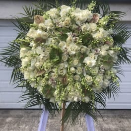 Large white floral standing spray with palm fronds and orchids
