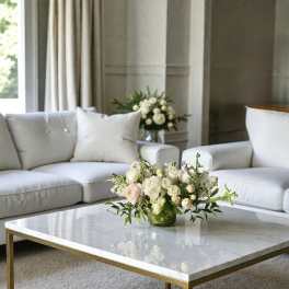 White and blush rose bouquet in a low glass vase on a coffee table