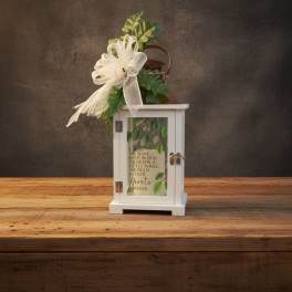 White memorial lantern with printed verse, topped with a white bow and green foliage.