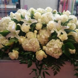 Large white floral arrangement with roses, lilies, and hydrangeas