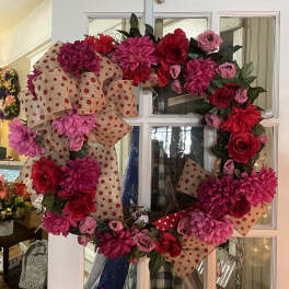 Pink and red floral wreath with burlap polka-dot ribbon on a white door