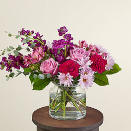 Pink and purple flowers arranged in a clear glass vase