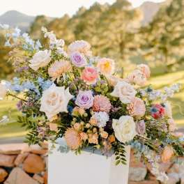 Pastel floral arrangement with roses and daisies in a white pedestal vase
