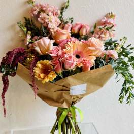 Bouquet of pink and peach flowers wrapped in brown paper