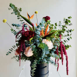Mixed floral arrangement in a black hatbox with bird-of-paradise and roses