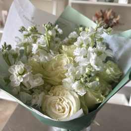 Bouquet of white roses and pale green blooms wrapped in mint paper