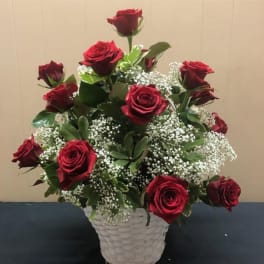 Red roses arranged in a white basket with baby's breath
