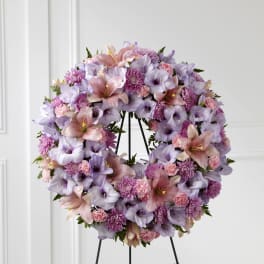 Large wreath of lavender and pink lilies, carnations, and mums on a metal easel stand