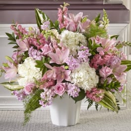 Large pink and white arrangement of lilies, roses, and hydrangeas in a white vase