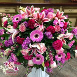 Large pink and white floral arrangement in a white pedestal vase