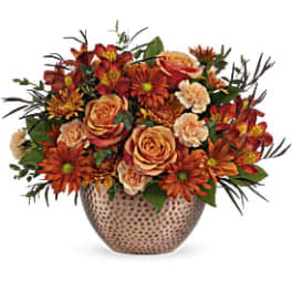 Orange and peach floral arrangement in a patterned vase