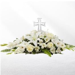 White floral casket spray with a clear cross centerpiece