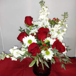 Red roses and white daisies in a dark glass vase