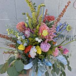 Handheld bouquet of mixed colorful flowers with blue ribbon