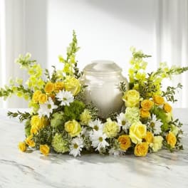 Yellow roses and white daisies arranged around a silver urn