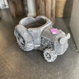 Silver tractor-shaped planter on a floor