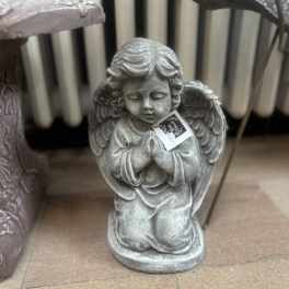 Small gray praying angel statue on the floor beside decorative planters
