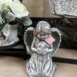 Silver angel figurine beside a white floral arrangement