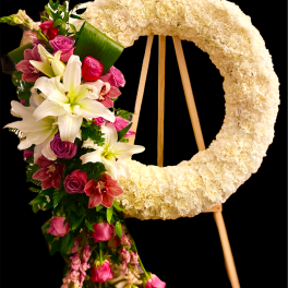 Floral wreath on an easel beside a cascading bouquet of lilies and roses