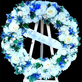 Heart-shaped floral wreath with white and blue flowers on a stand