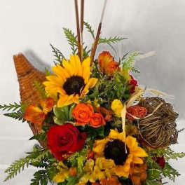 Mixed bouquet with sunflowers, roses, and orange blooms in a woven basket