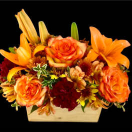 Orange roses and lilies arranged in a rectangular wooden container