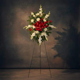 Standing floral spray with red roses and white flowers on a metal easel