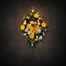 Yellow and white floral standing wreath with a gold bow on an easel