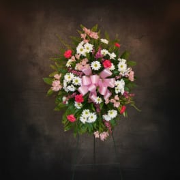 Standing floral spray with pink and white flowers and a pink ribbon bow