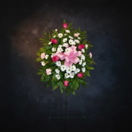Standing floral wreath with pink roses, white daisies, and a pink bow