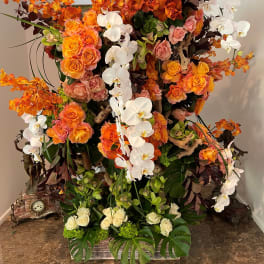 Large floral arrangement with orange roses and white orchids