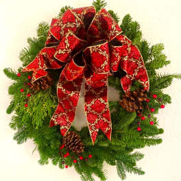 Christmas wreath with a red patterned bow, pinecones, and evergreen branches