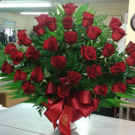 Large bouquet of red roses with a red ribbon in a white vase